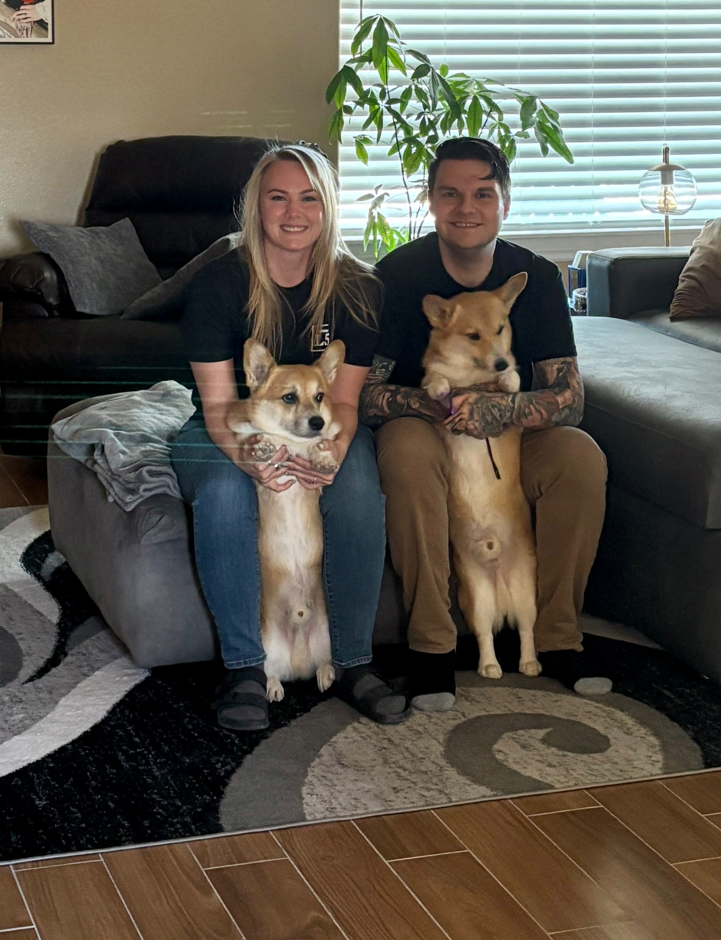 Randi and her husband at home holding their two corgis